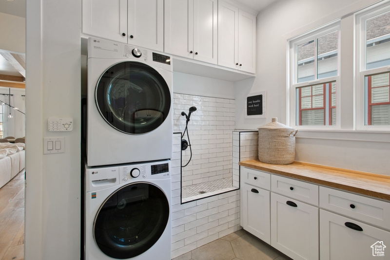 Laundry area featuring cabinet space and stacked washer / drying machine