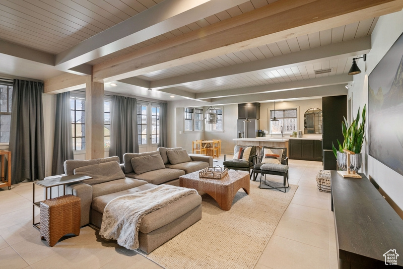 Living room with light tile patterned floors and a wood ceiling with exposed beams