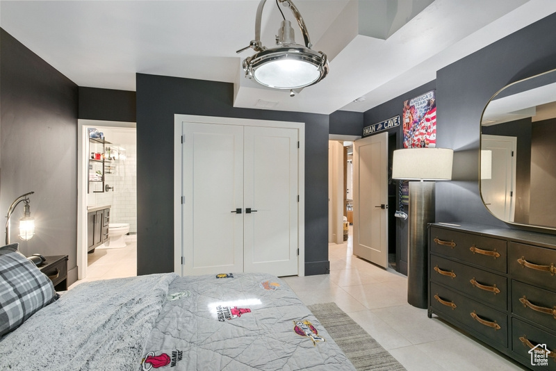 Bedroom with light tile patterned floors, a closet, and ensuite bathroom