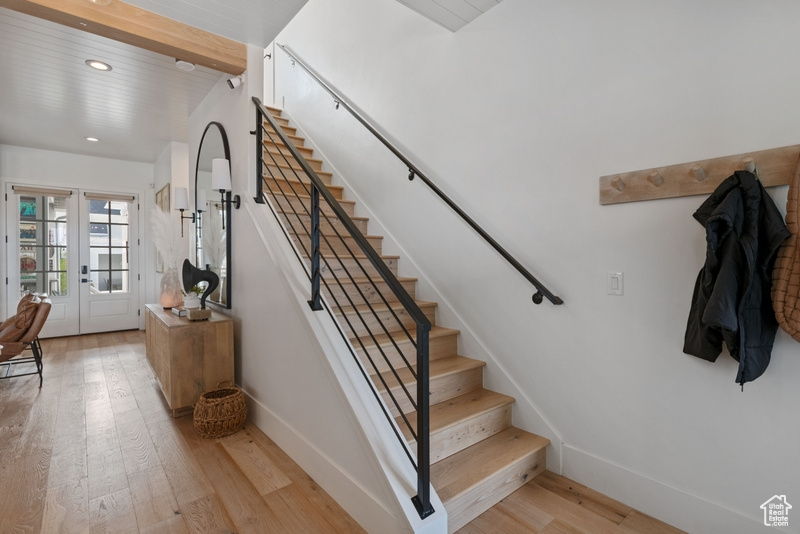 Stairway with wood finished floors, recessed lighting, french doors, and beamed ceiling