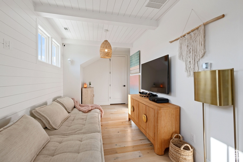 Living room featuring light wood-style flooring, a wood ceiling with exposed beams, and wooden walls
