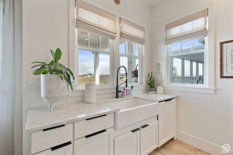 Kitchen featuring light stone counters, white cabinetry, and light wood-type flooring