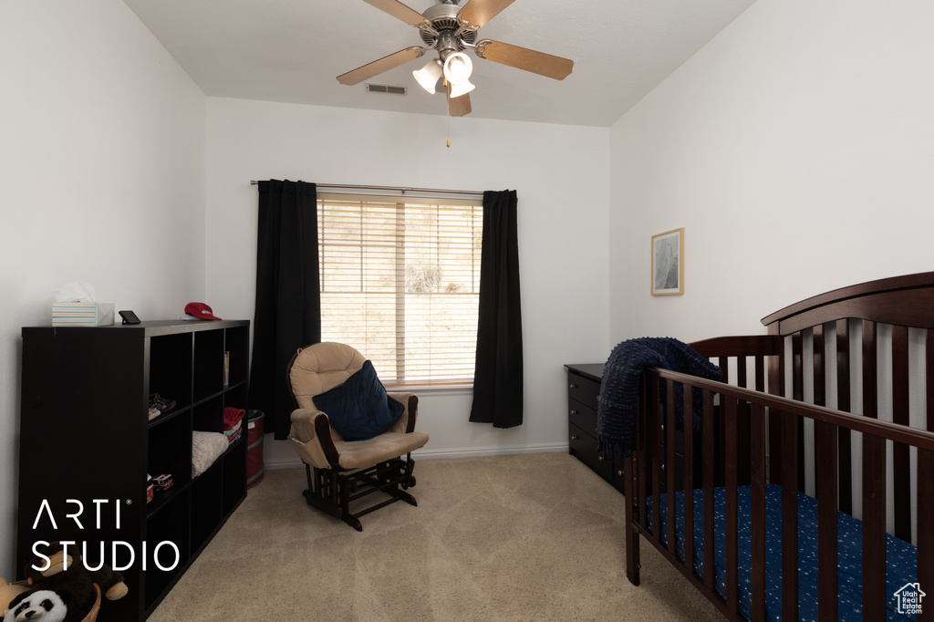 Bedroom featuring carpet floors, a nursery area, and a ceiling fan