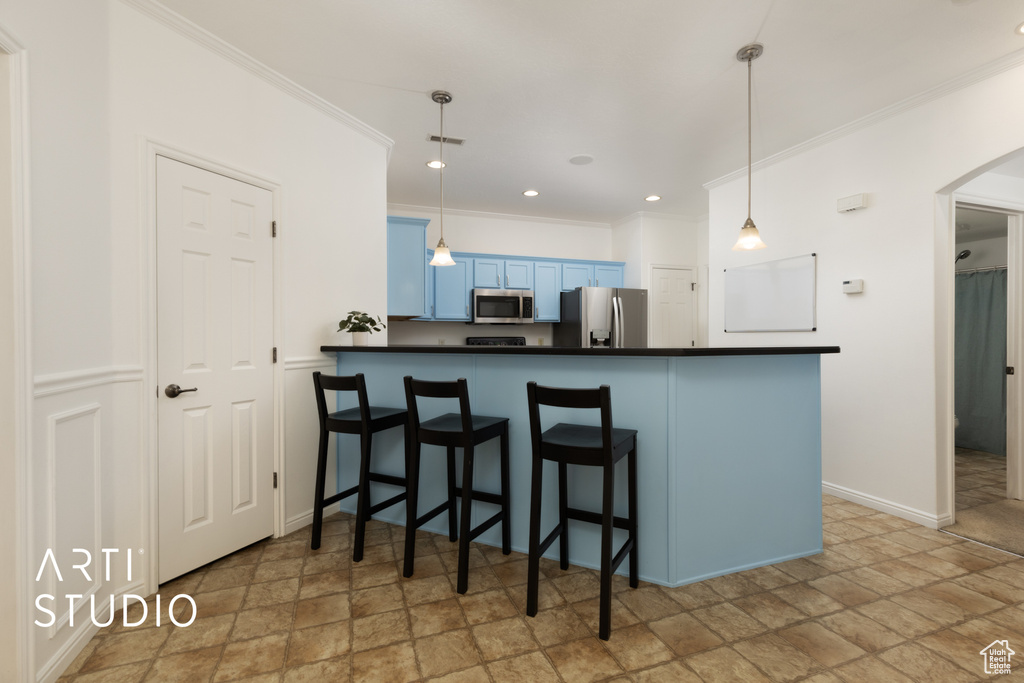 Kitchen featuring stainless steel appliances, stone finish floors, dark countertops, blue cabinets, and crown molding