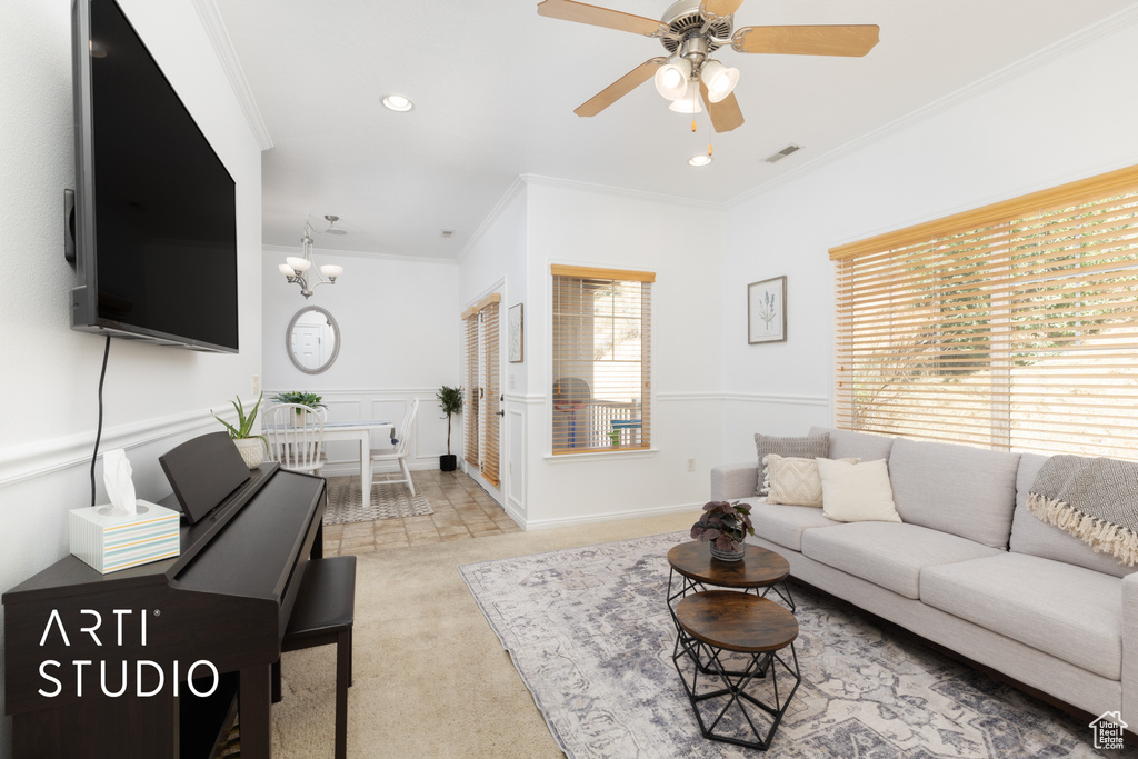 Living room with carpet floors, ornamental molding, ceiling fan, recessed lighting, and a chandelier