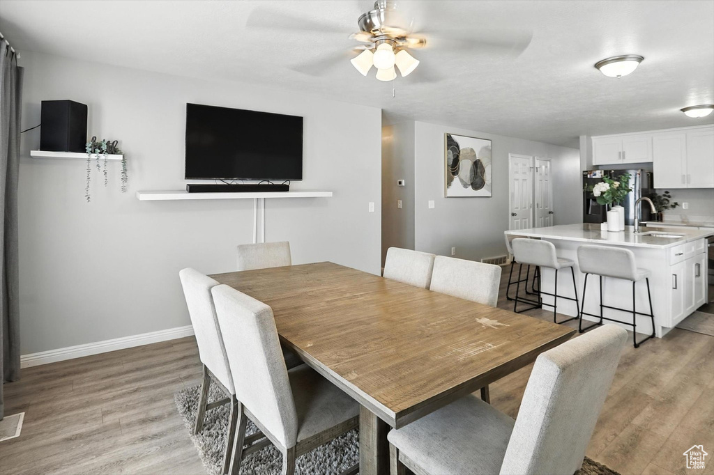 Dining area with a ceiling fan and light wood-style flooring