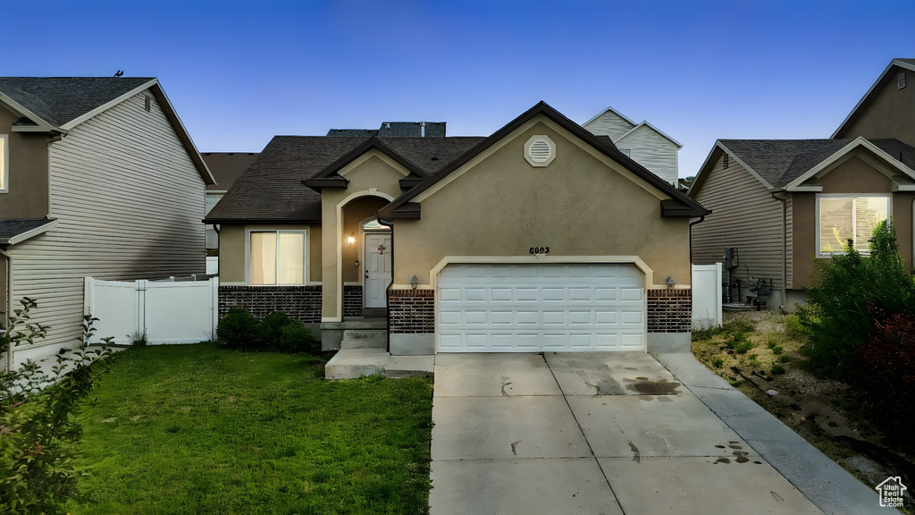 Traditional home with brick siding, a garage, driveway, and stucco siding