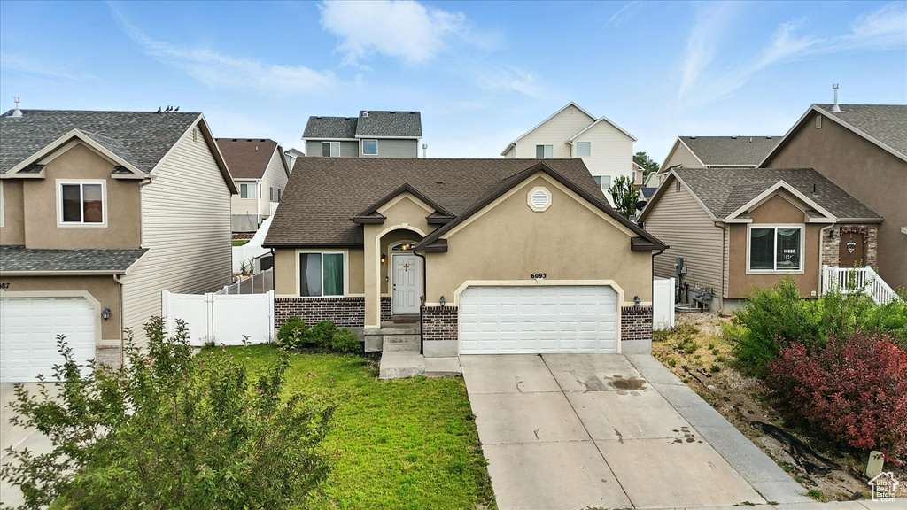 Traditional-style house with driveway, an attached garage, stucco siding, a residential view, and roof with shingles