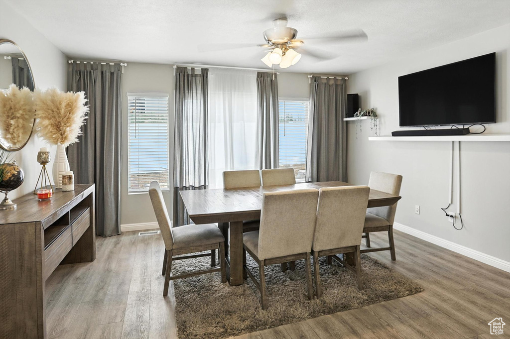 Dining area with healthy amount of natural light, wood finished floors, and ceiling fan