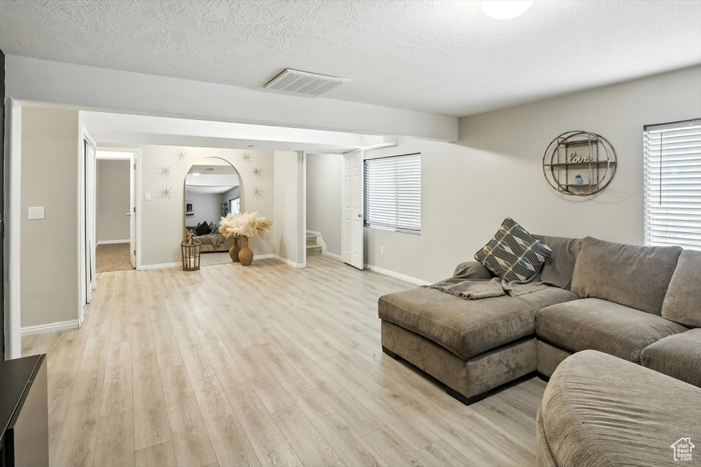 Living area featuring stairs, light wood finished floors, healthy amount of natural light, and a textured ceiling