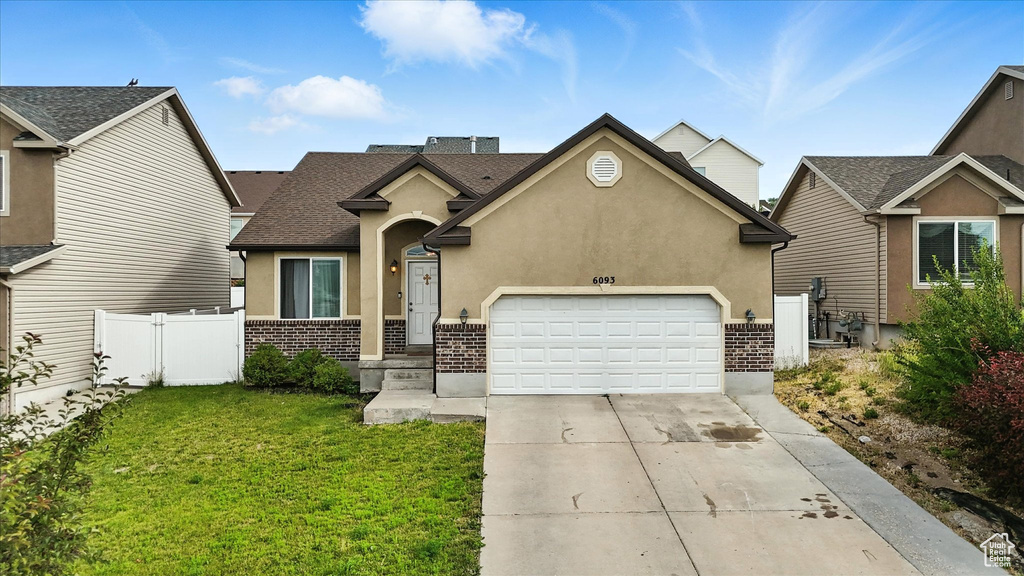 Traditional-style home with an attached garage, brick siding, driveway, stucco siding, and a shingled roof