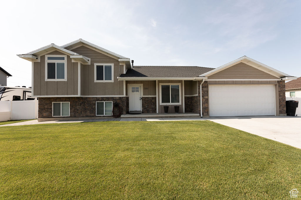 Split level home with an attached garage, driveway, board and batten siding, and a shingled roof