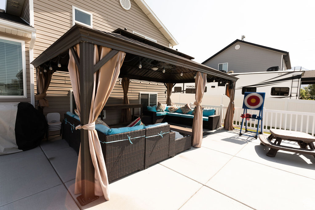 Fenced backyard featuring a gazebo, an outdoor hangout area, and a patio