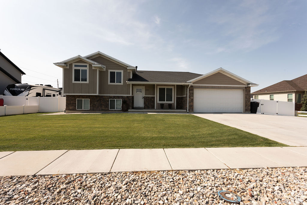 Tri-level home featuring concrete driveway, a garage, and a gate