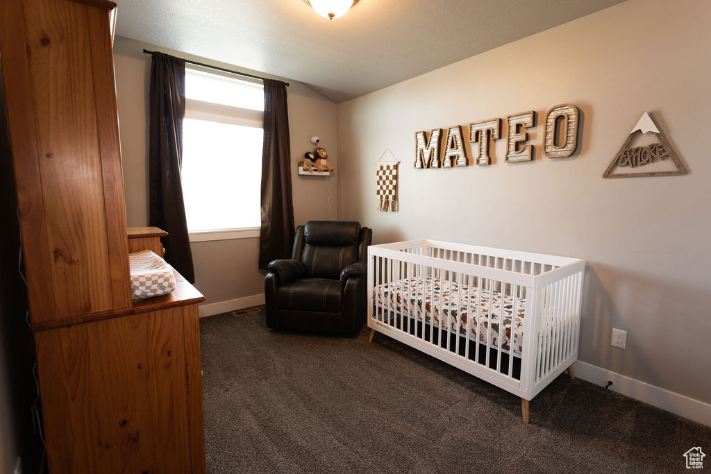 Carpeted bedroom with baseboards and a nursery area