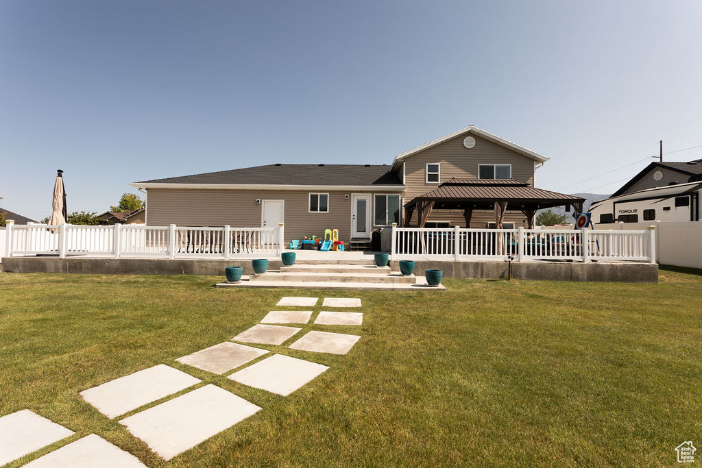 Back of house featuring a gazebo and a yard
