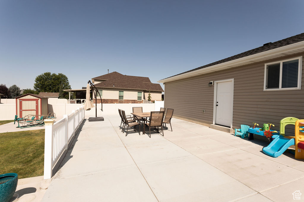 Fenced backyard featuring a patio area, outdoor dining area, and a shed