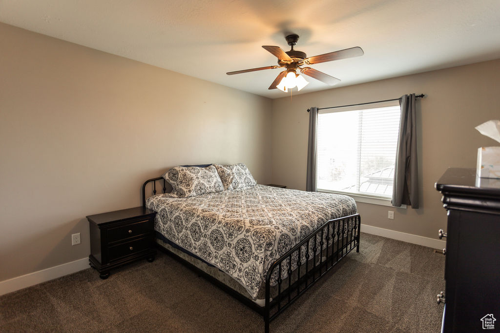 Bedroom with dark colored carpet and ceiling fan