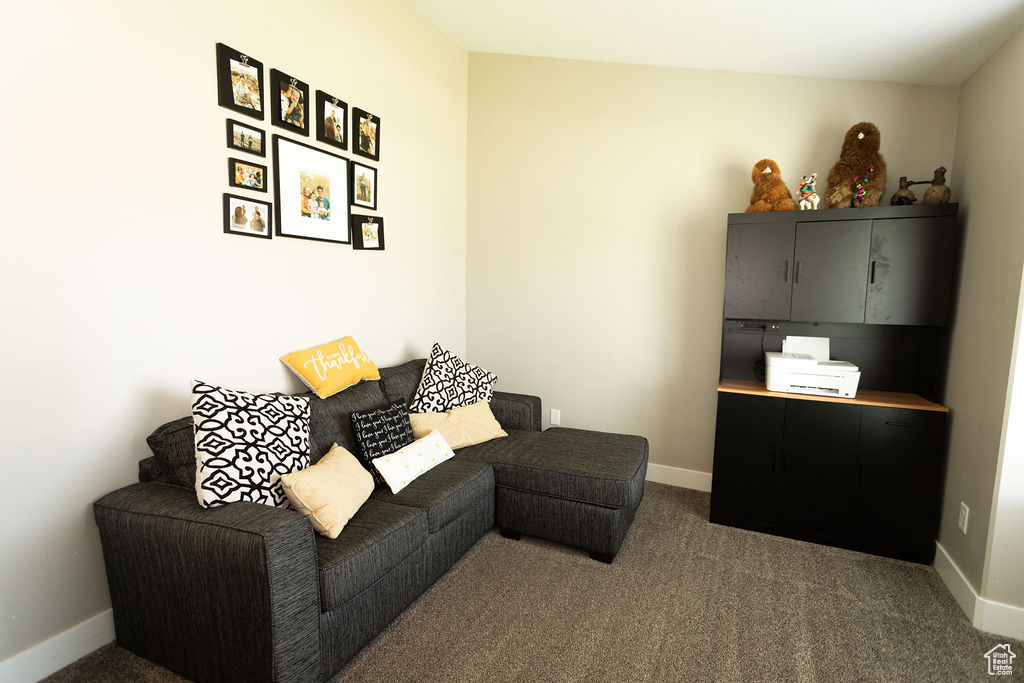 Living room featuring dark colored carpet and baseboards