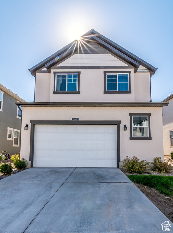 Traditional home with a garage, concrete driveway, and stucco siding