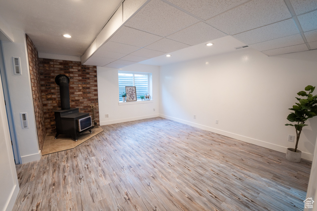 Unfurnished living room with a wood stove, wood finished floors, recessed lighting, and a drop ceiling