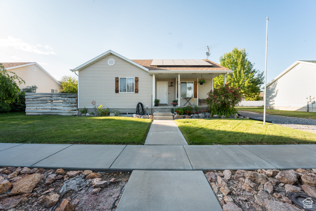 Bungalow-style house featuring roof mounted solar panels, a porch, and roof with shingles