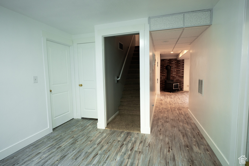 Hallway with wood finished floors, stairway, and a paneled ceiling