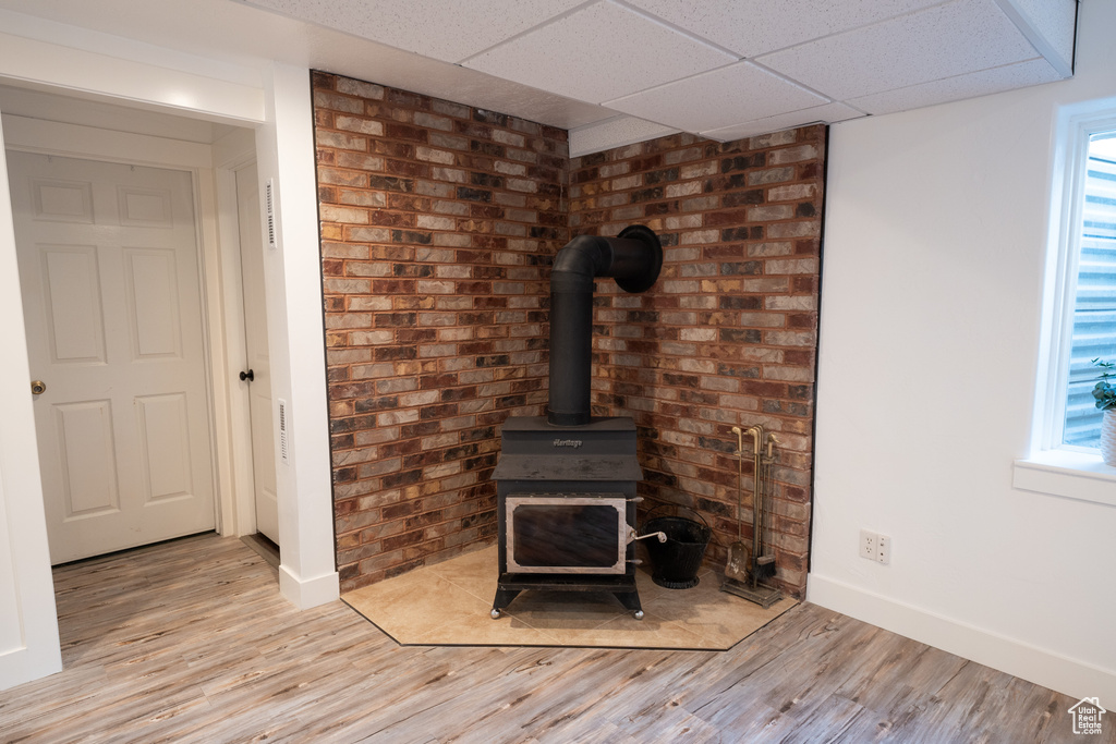 Detailed view of wood finished floors, a wood stove, and a drop ceiling