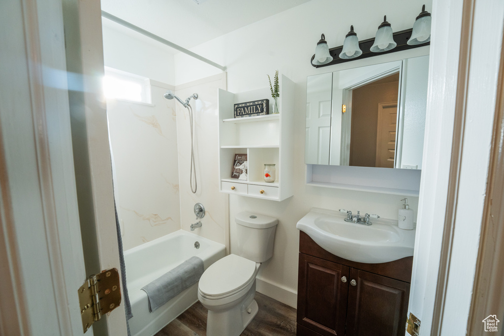 Bathroom featuring washtub / shower combination, vanity, and wood finished floors