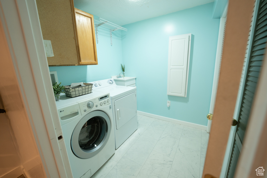 Laundry area with washer and clothes dryer, light marble finish flooring, and cabinet space