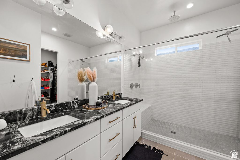 Full bathroom featuring double vanity, tiled shower, tile patterned floors, a spacious closet, and recessed lighting