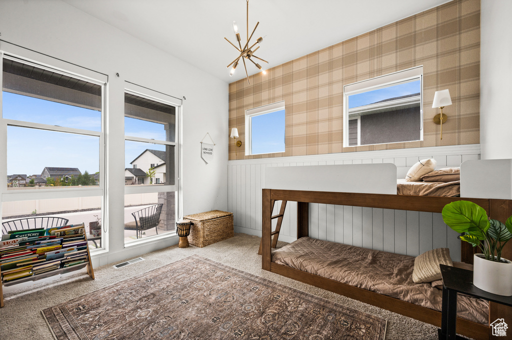 Bedroom featuring a chandelier, carpet flooring, and wainscoting