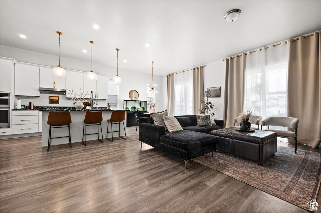 Living area with healthy amount of natural light, recessed lighting, dark wood finished floors, and a chandelier