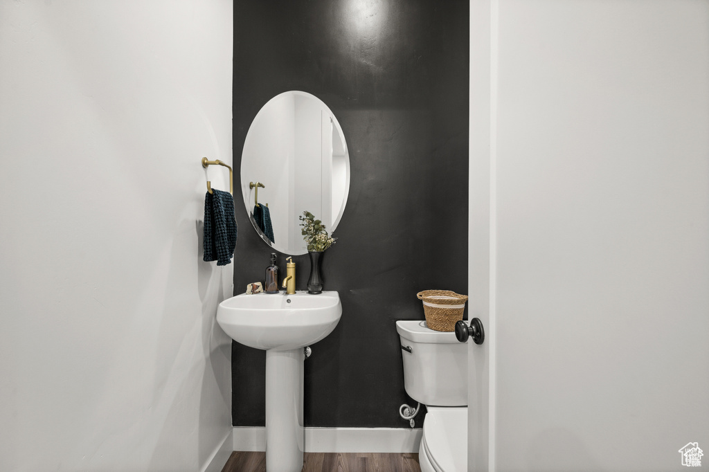 Half bathroom with wood finished floors and toilet