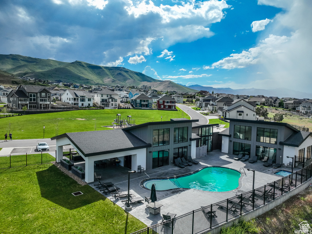Community pool with a residential view, a fenced backyard, and a mountain view