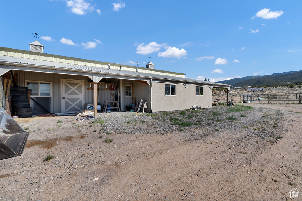 Rear view of house with an exterior structure, a mountain view, an outdoor structure, a chimney, and board and batten siding