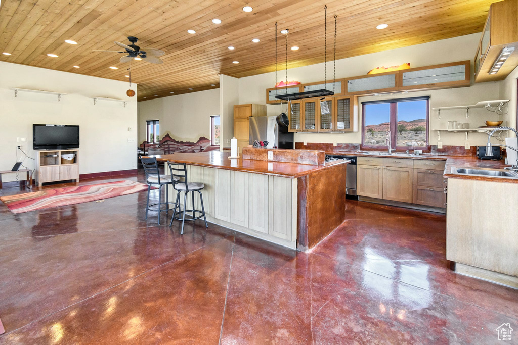 Kitchen with freestanding refrigerator, wood ceiling, stainless steel dishwasher, a center island, and open floor plan