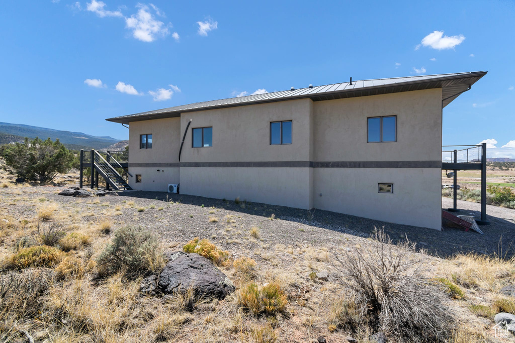 Rear view of property featuring a metal roof, a standing seam roof, stucco siding, stairs, and a mountain view