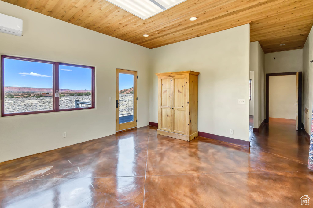 Spare room with finished concrete flooring, wood ceiling, a wall mounted AC, and recessed lighting