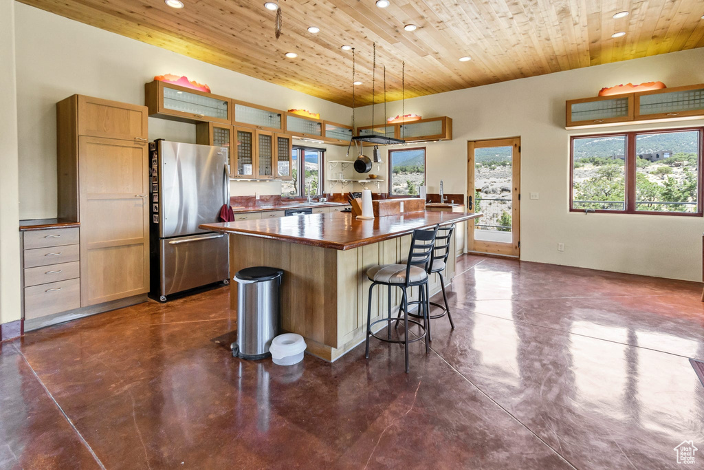 Kitchen featuring freestanding refrigerator, recessed lighting, wood ceiling, concrete floors, and a kitchen island