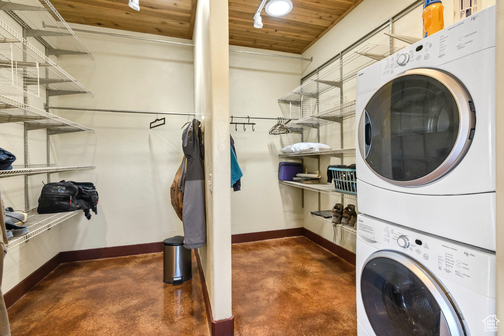 Washroom with stacked washer / drying machine and wooden ceiling