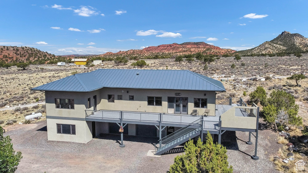 Rear view of property featuring stucco siding, stairs, a metal roof, a deck with mountain view, and a standing seam roof
