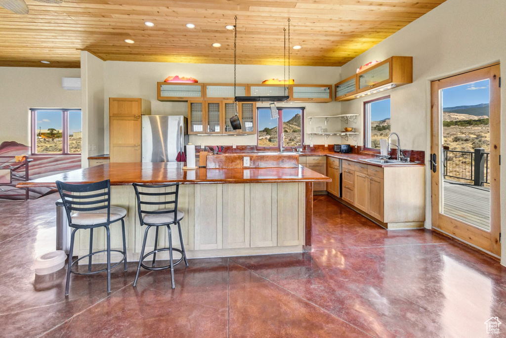 Kitchen featuring freestanding refrigerator, wooden ceiling, concrete flooring, recessed lighting, and a center island