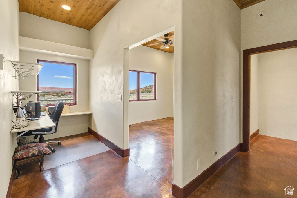 Home office with concrete floors, plenty of natural light, a towering ceiling, ceiling fan, and wood ceiling
