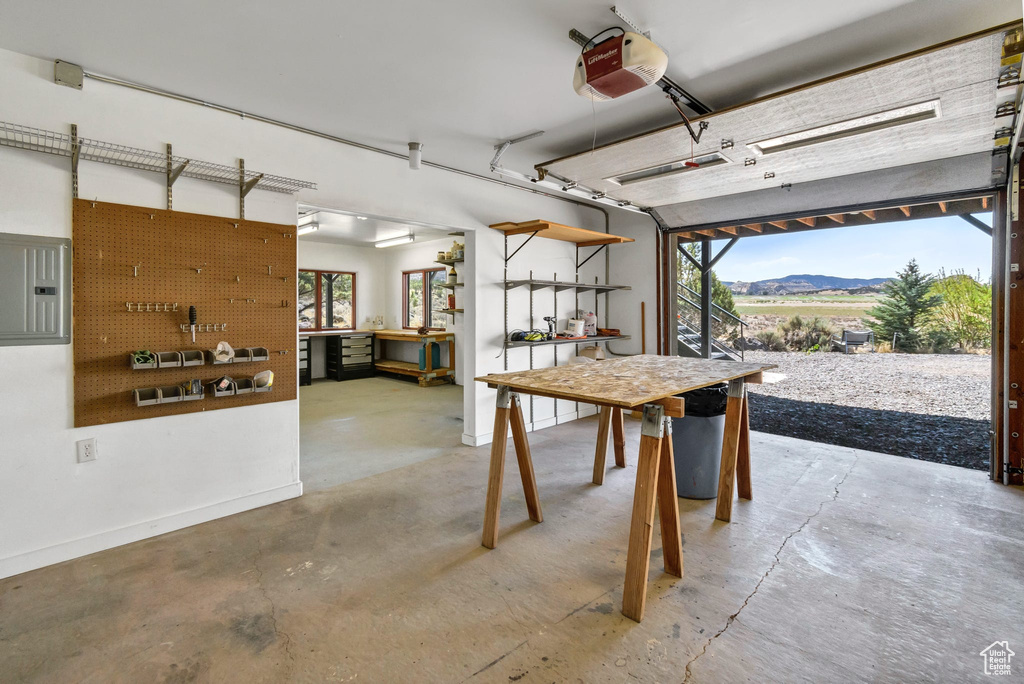 Garage with a garage door opener, a workshop area, a mountain view, and electric panel