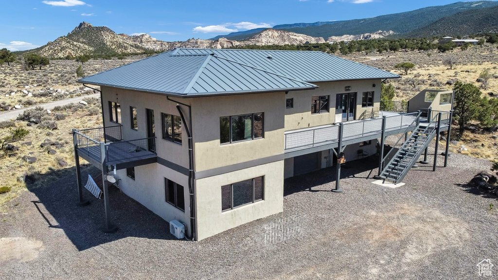 Back of property with a standing seam roof, stucco siding, a mountain view, a balcony, and a metal roof