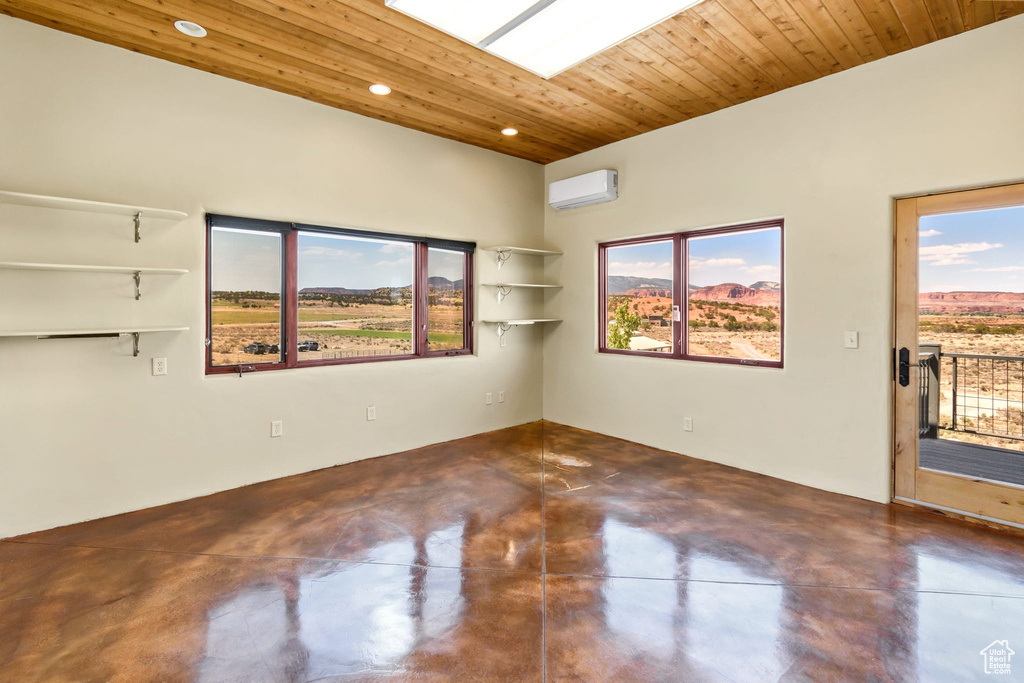 Empty room with a wall mounted AC, finished concrete flooring, recessed lighting, and wooden ceiling