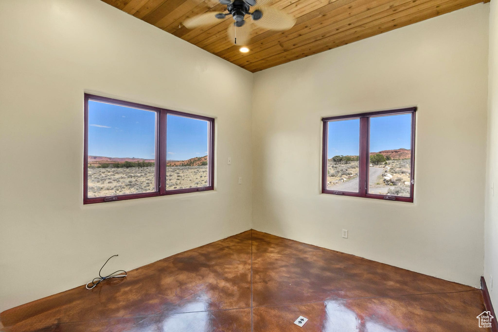 Unfurnished room featuring wood ceiling, plenty of natural light, finished concrete flooring, and a ceiling fan