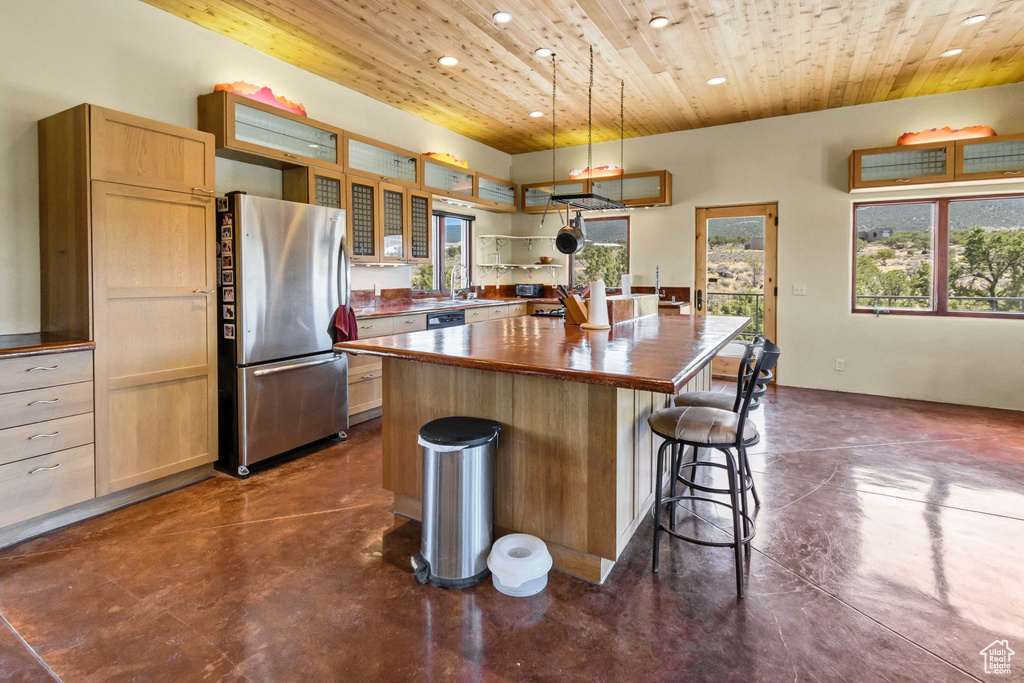Kitchen featuring freestanding refrigerator, wooden ceiling, finished concrete floors, recessed lighting, and a kitchen bar