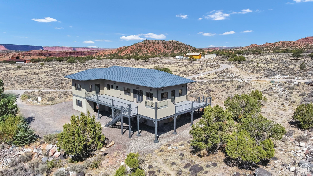 Rear view of house featuring a desert view, a metal roof, a rural view, stairway, and a balcony
